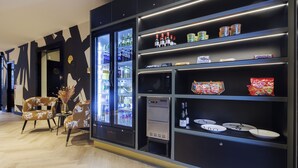 Ein modernes Interieur mit einer Sitzecke, einem Getränkespender und Regalen voller Snacks und Würzmittel.