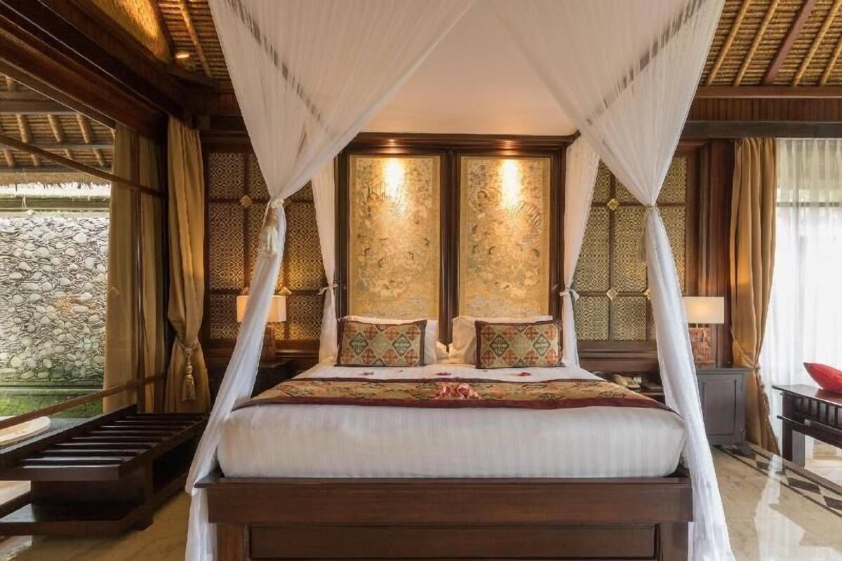 A large bed with a canopy, a stone wall outside, and a wooden floor.