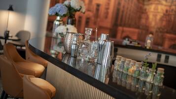 A bar area with a polished bar counter, a selection of bar tools, and a vase with flowers.