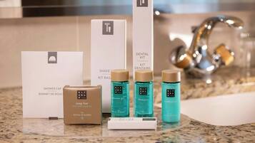 Un meuble de salle de bain avec un bonnet de douche, un kit de rasage, un savon et trois flacons de produits Rituals.