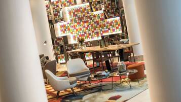 Een moderne bibliotheek met een grote boekenkast, comfortabele zitplaatsen en een centrale tafel.