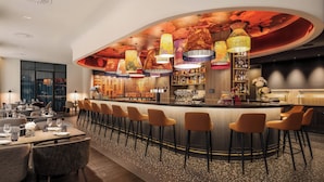A bar area with a curved counter, multiple bar stools, and a variety of bottles and glasses.