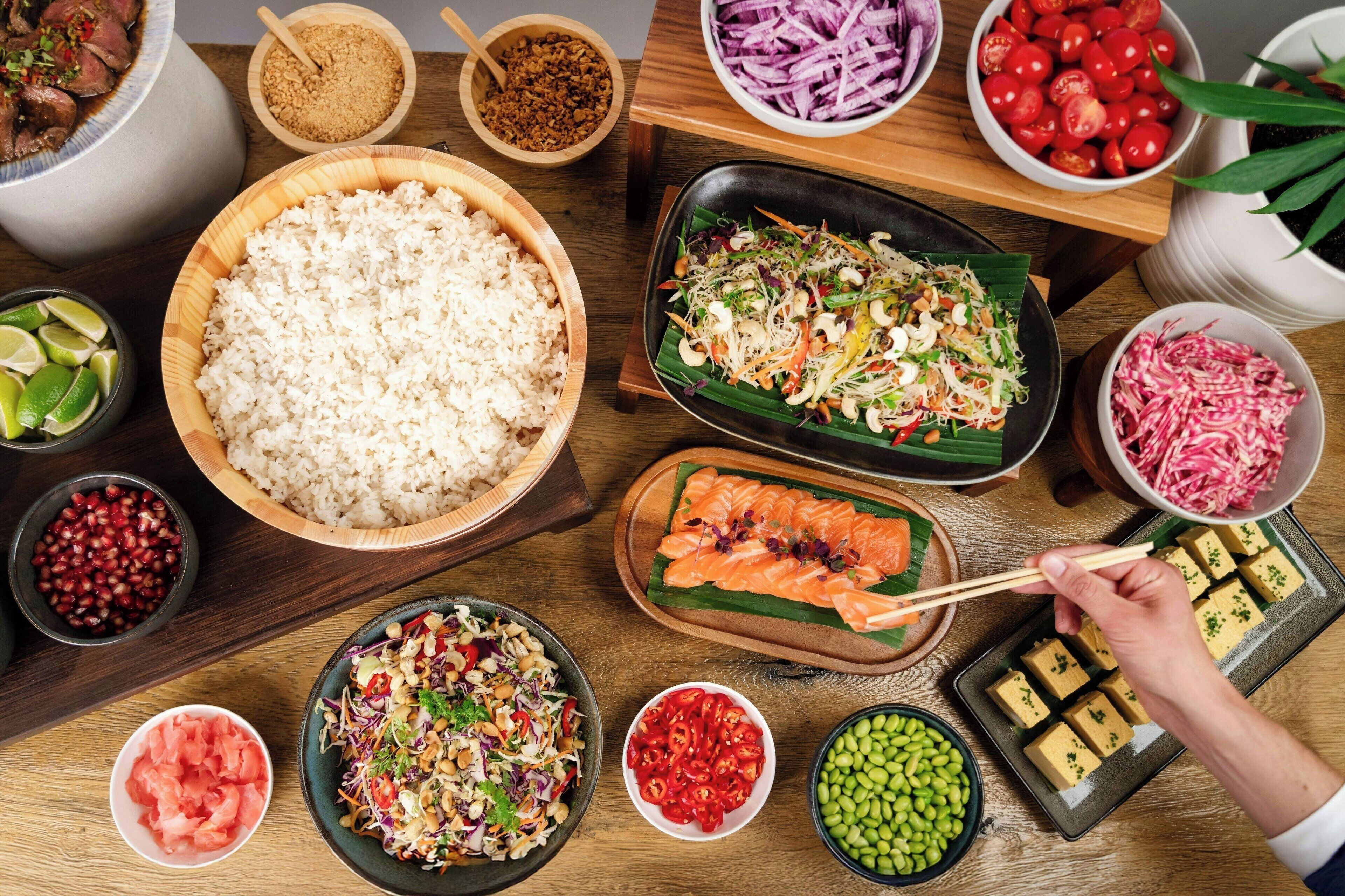 Een tafel met diverse gerechten, waaronder rijst, salades en vis.