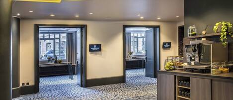A hotel lobby with a patterned carpet, a reception desk with amenities, and two doors leading to other areas.