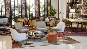 A modern living room with a sofa, armchairs, a coffee table, and a dining area with a table and chairs.