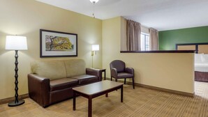 A hotel room with a sofa, armchair, coffee table, and a painting on the wall. - Extended Stay America Suites St Louis St Peters (St. Peters)