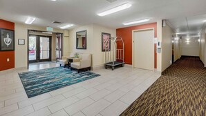 A hotel lobby with a reception desk, a wheelchair, and an exit sign. - Extended Stay America Suites St Louis St Peters (St. Peters)