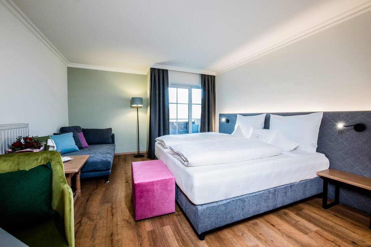 Una habitación de hotel con una cama grande, un sofá, una mesita y un banco.