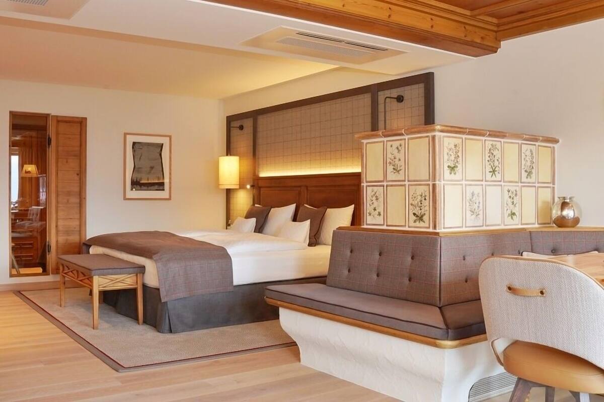 Una habitación de hotel con una cama grande, un sofá, una mesita pequeña y un mueble con motivos florales.