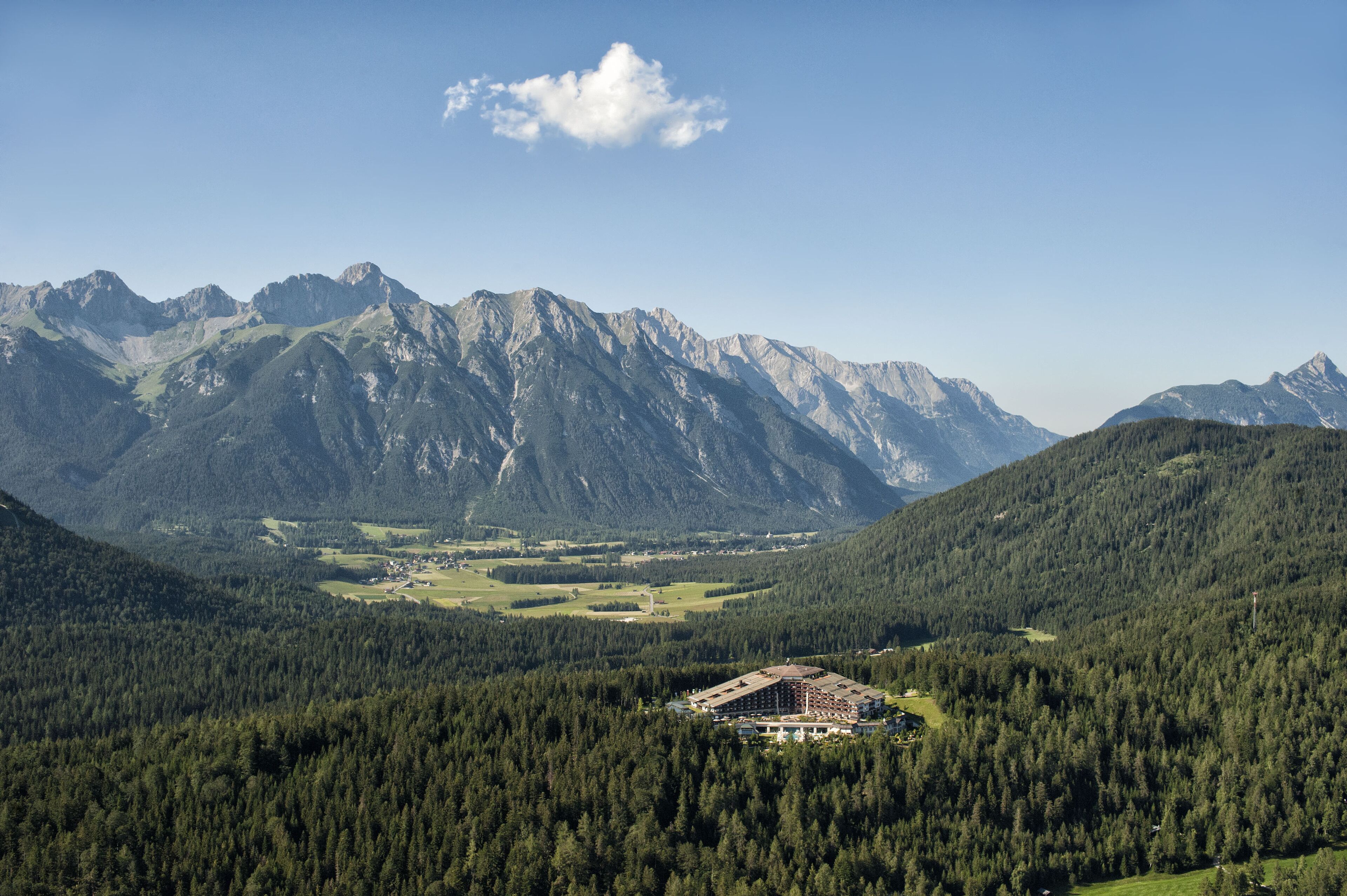 A mountain lodge with a large building surrounded by dense forest and mountains in the background.