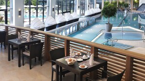 Uma área de refeições junto à piscina, com mesas, cadeiras e vista para a piscina.