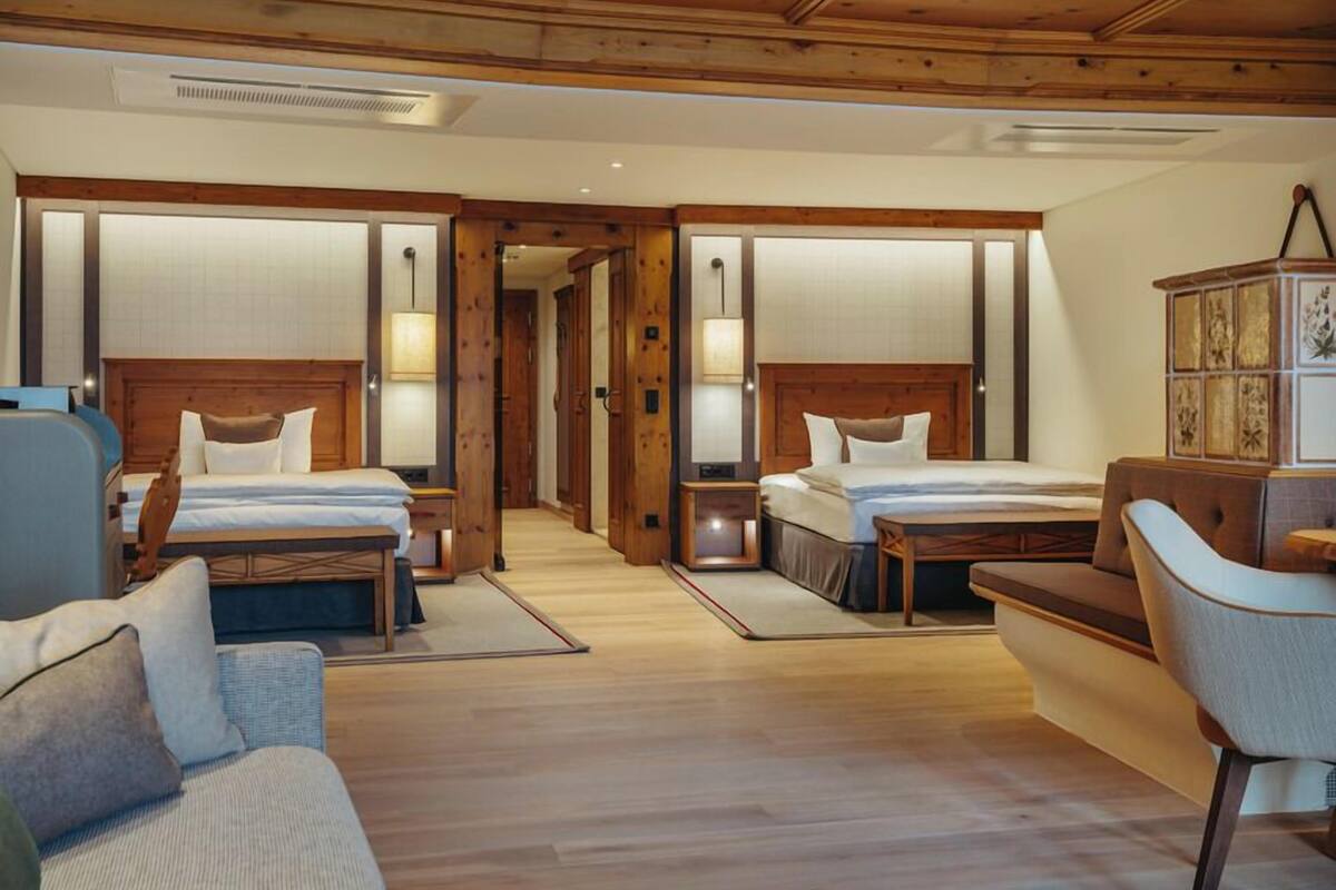 Habitación de hotel con dos camas, un sofá, un armario y techo de madera.
