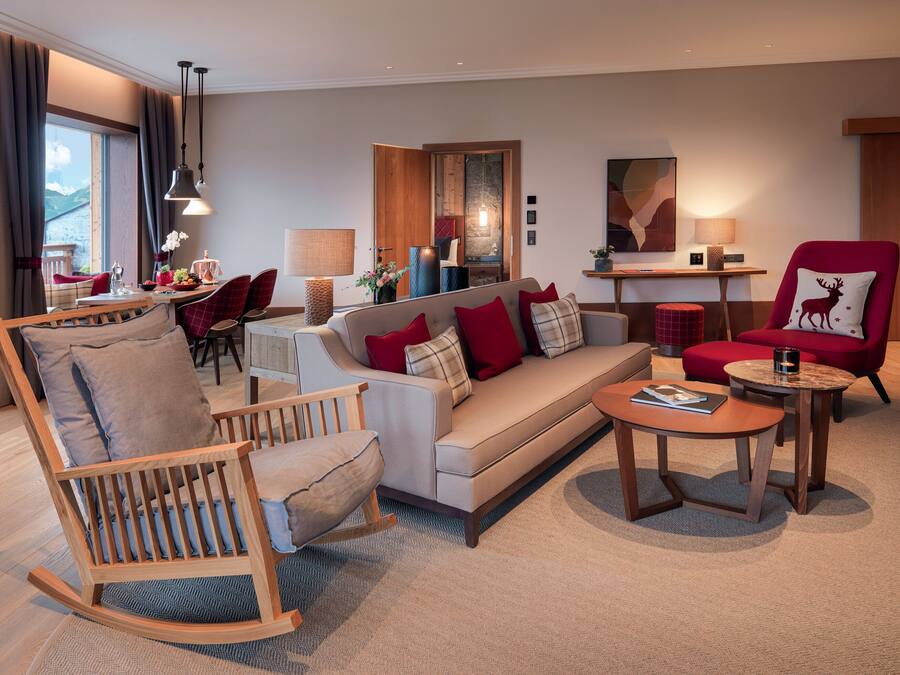 A modern living room with a sofa, chairs, a coffee table, and a dining area with a table and chairs.