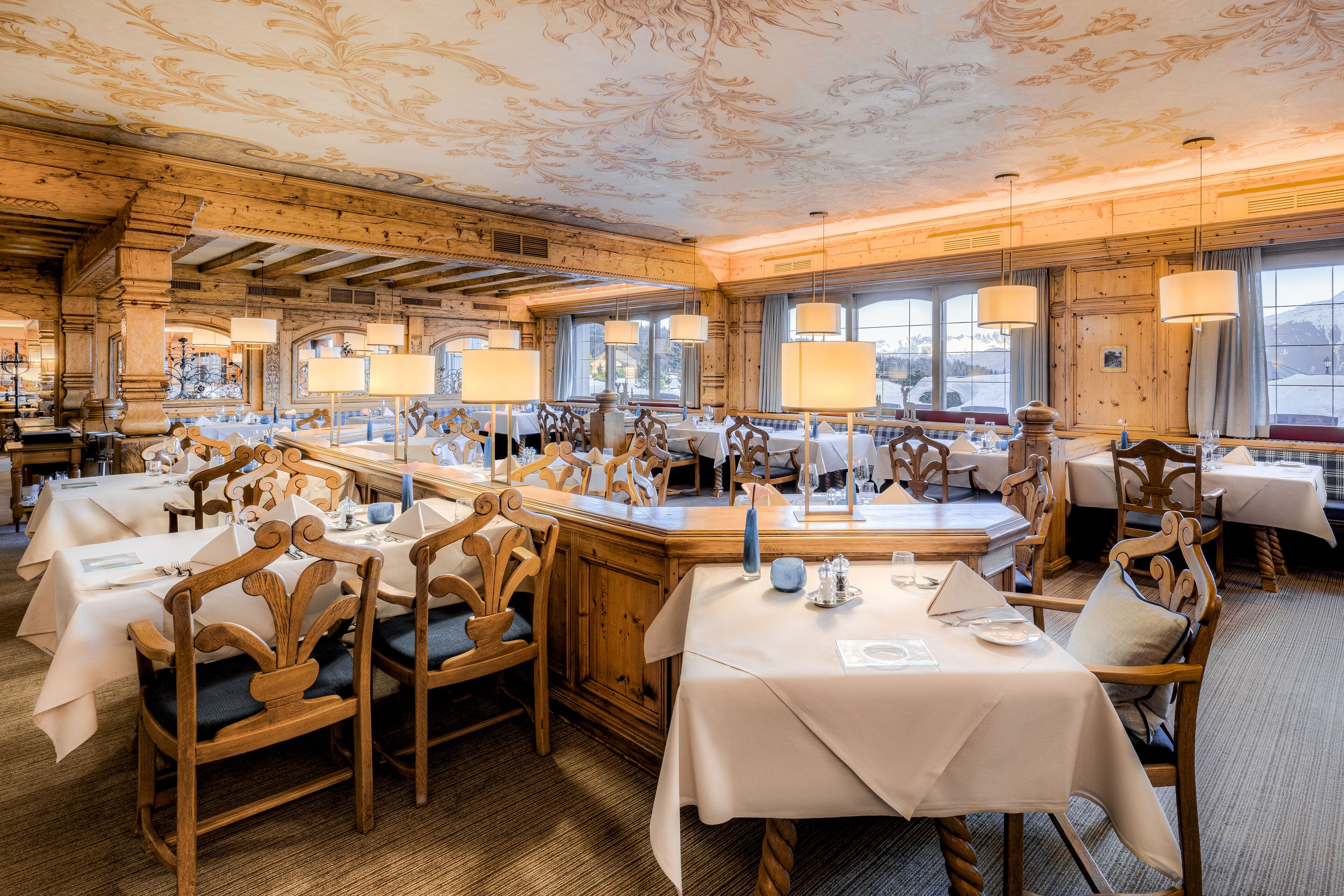 Un restaurante con muebles de madera, manteles blancos y candelabros.