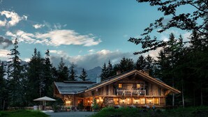 A rustic wooden cabin with a balcony, surrounded by dense forest and mountains in the background. - Interalpen-Hotel Tyrol GmbH (Telfs)
