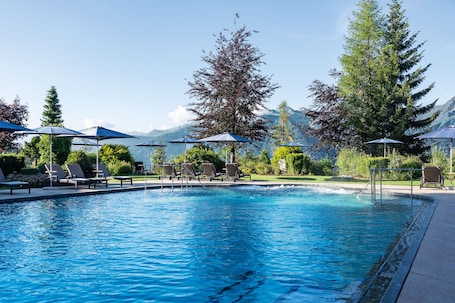 Una piscina techada, una piscina al aire libre, sombrillas