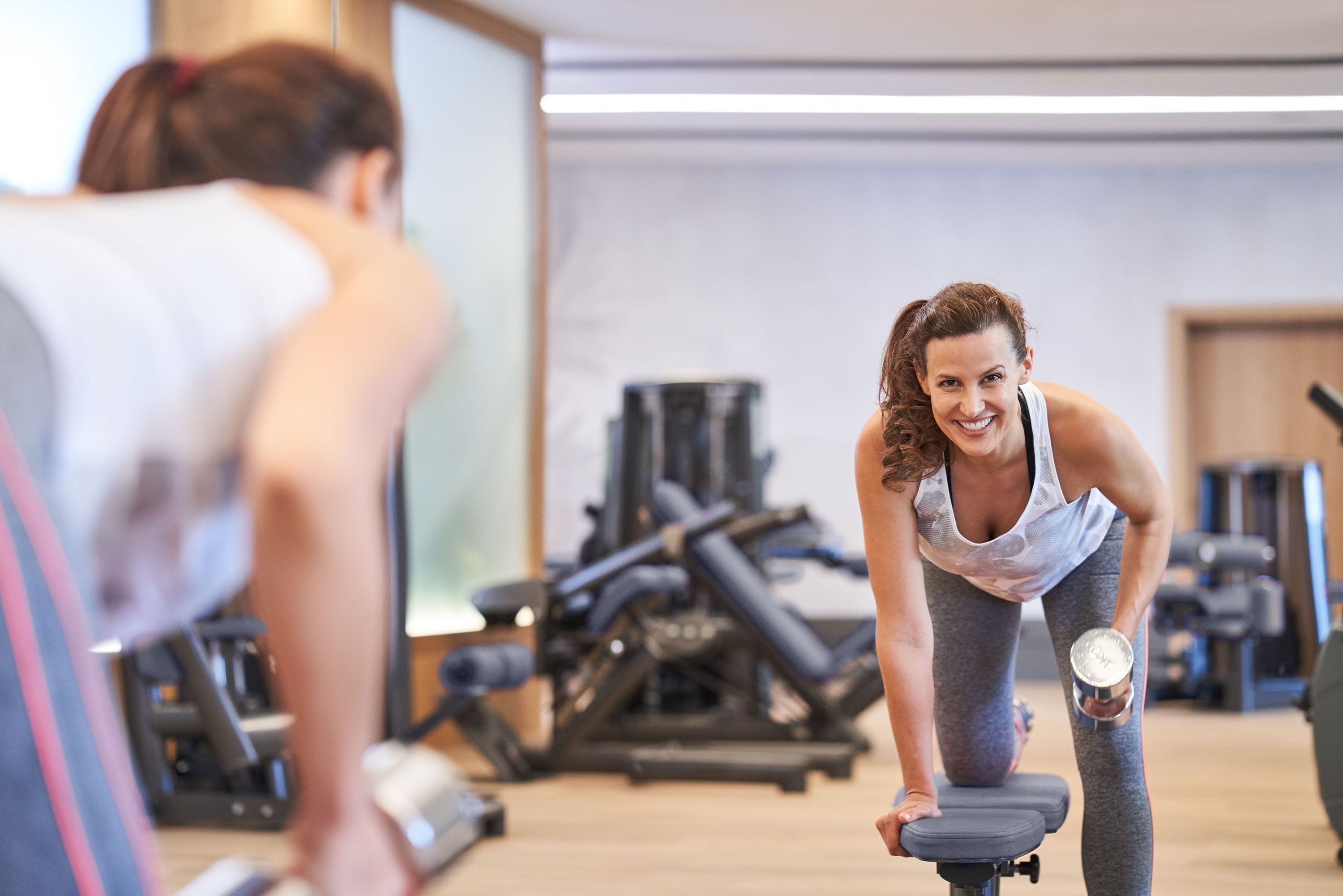 A gym with exercise equipment and a person using a stationary bike.