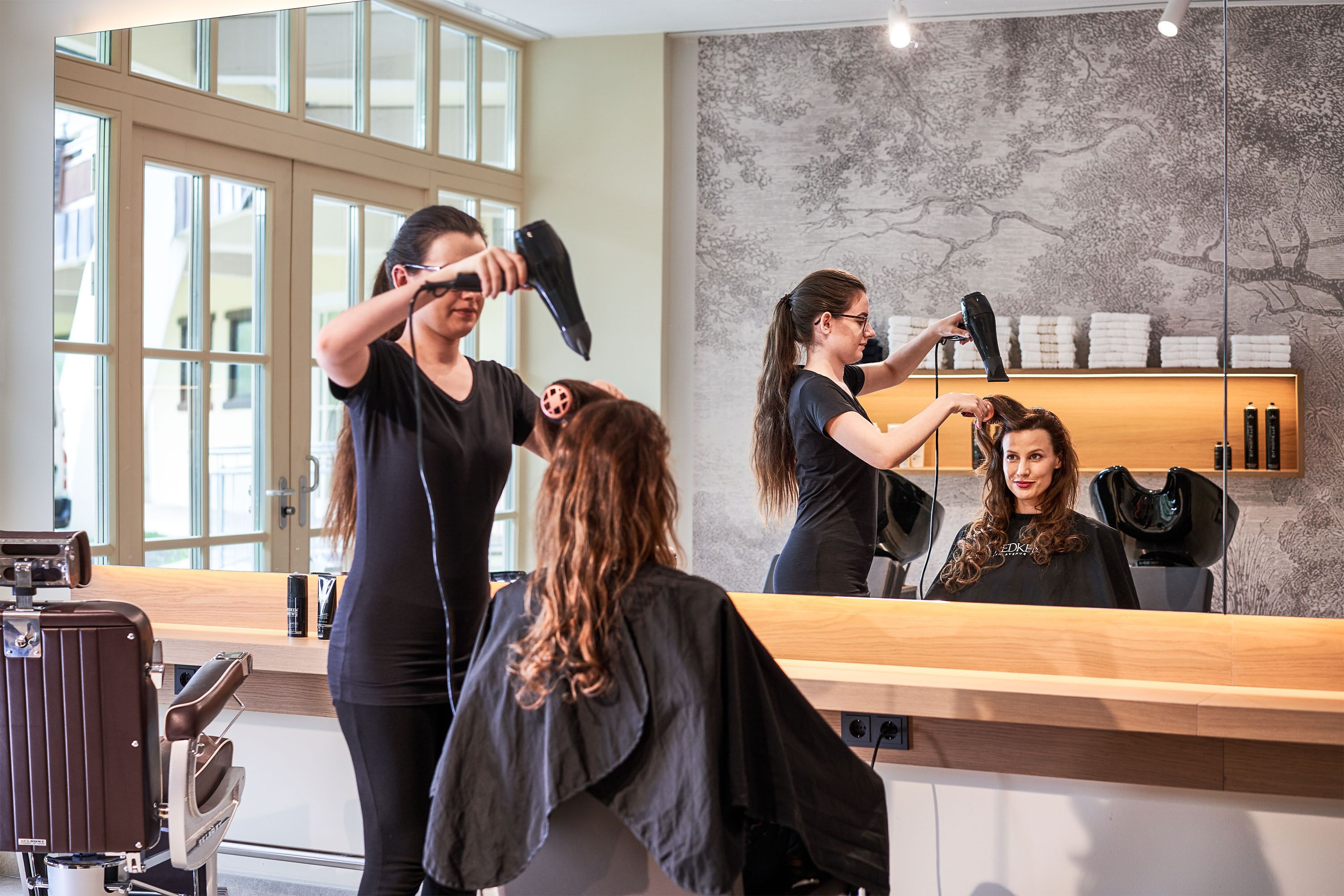 A hair salon with a large mirror, salon chairs, and a counter with hair products.