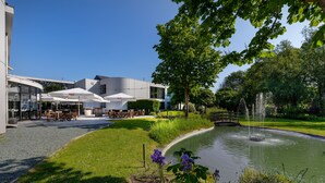 A modern building with outdoor seating and a fountain. - Hotel Ter Elst (Edegem)