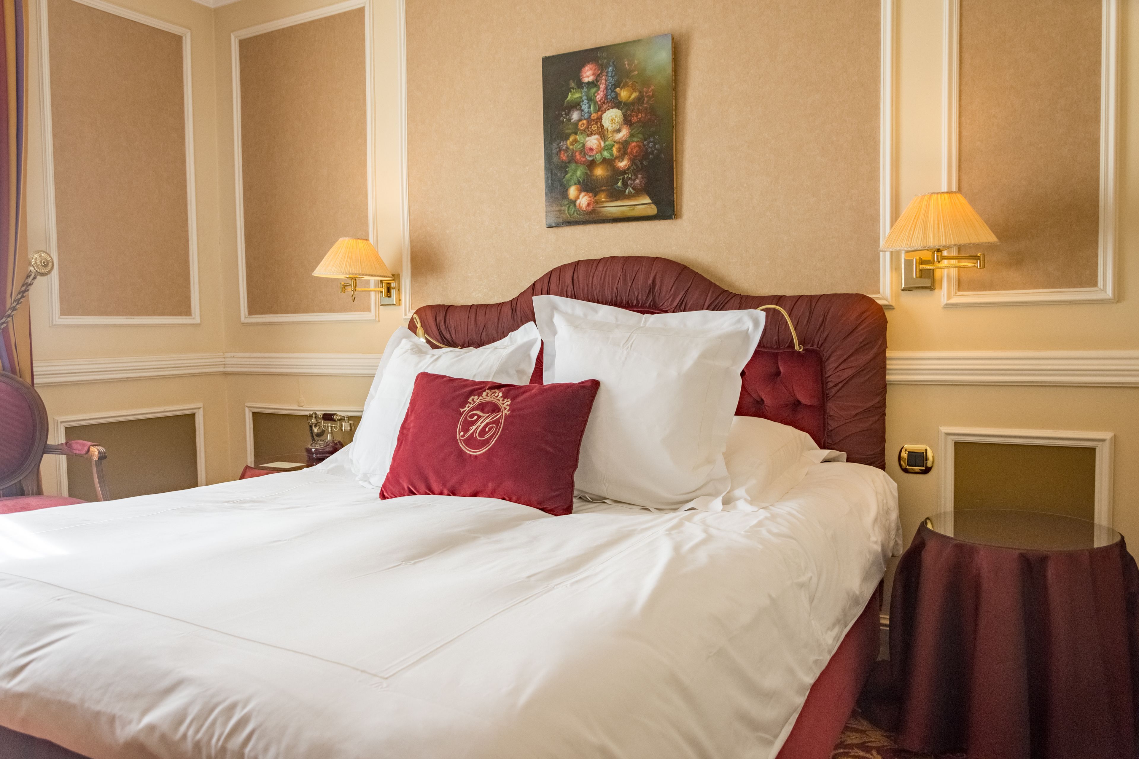 Een hotelkamer met een groot bed, twee bedlampen, een schilderij aan de muur en een kleine tafel.