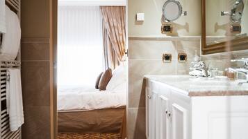 A hotel room with a bed, a bathroom with a sink and mirror, and a window with curtains.