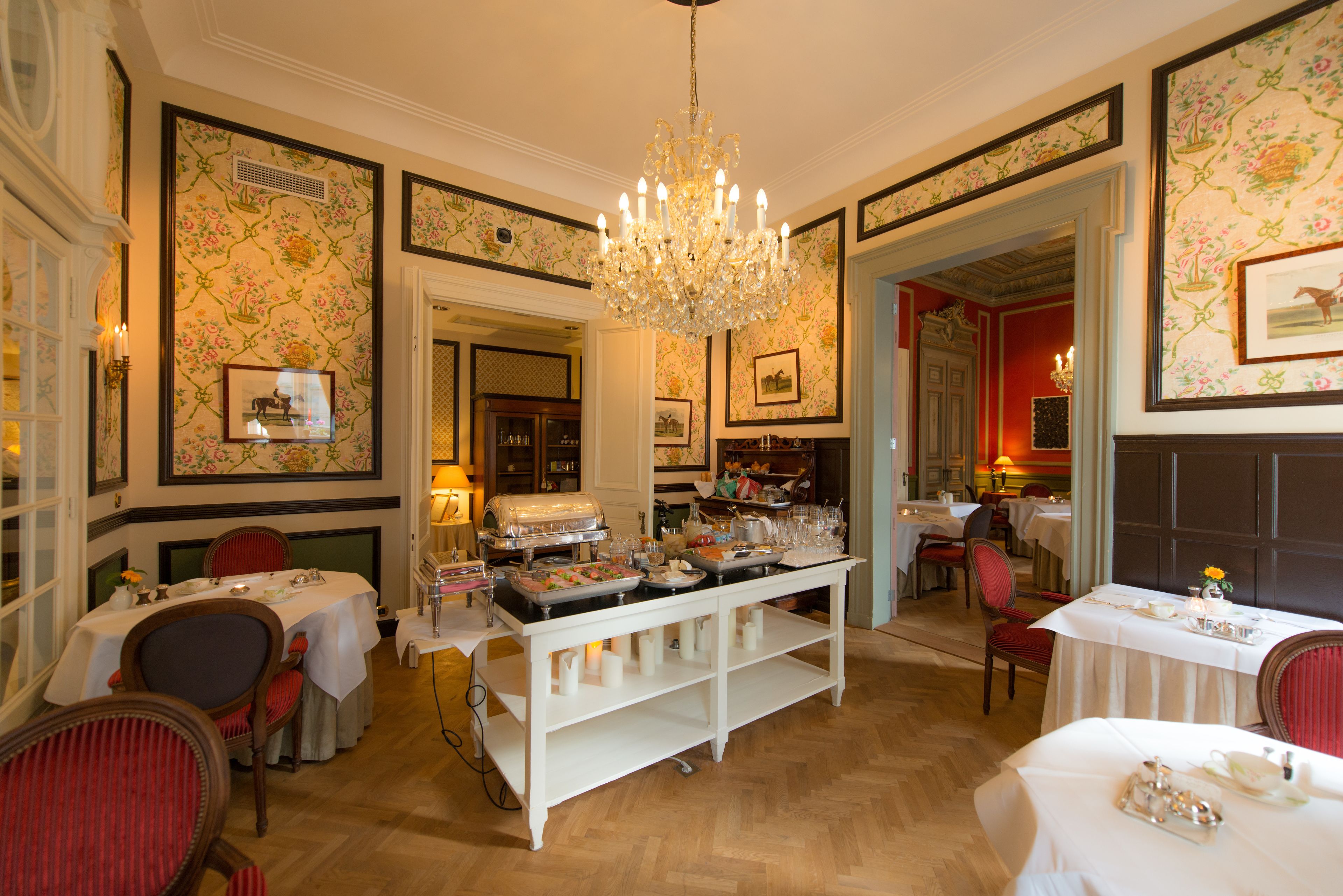 A dining area with a buffet setup, multiple tables, and chairs.