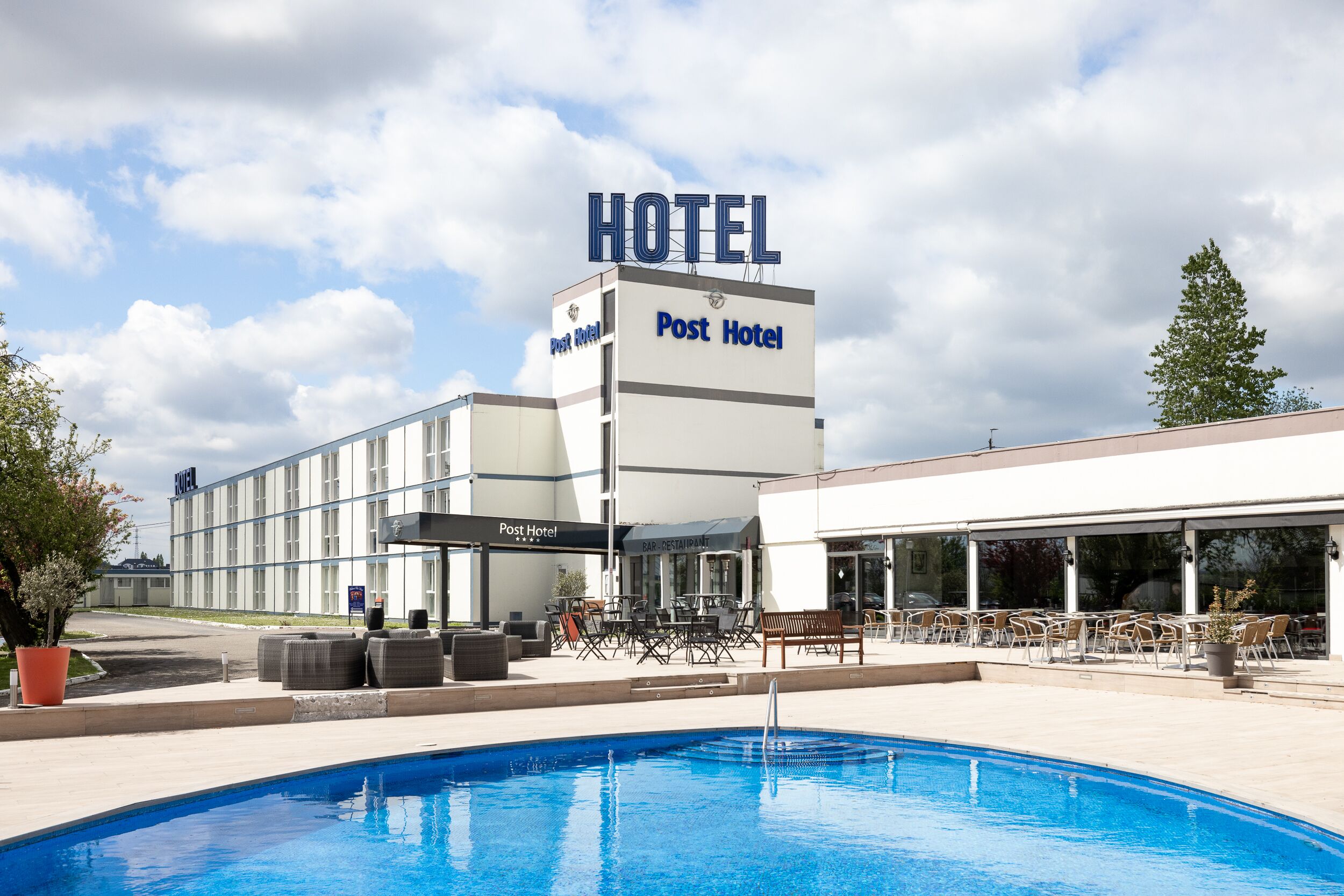 A hotel with a pool area, outdoor seating, and a bar.