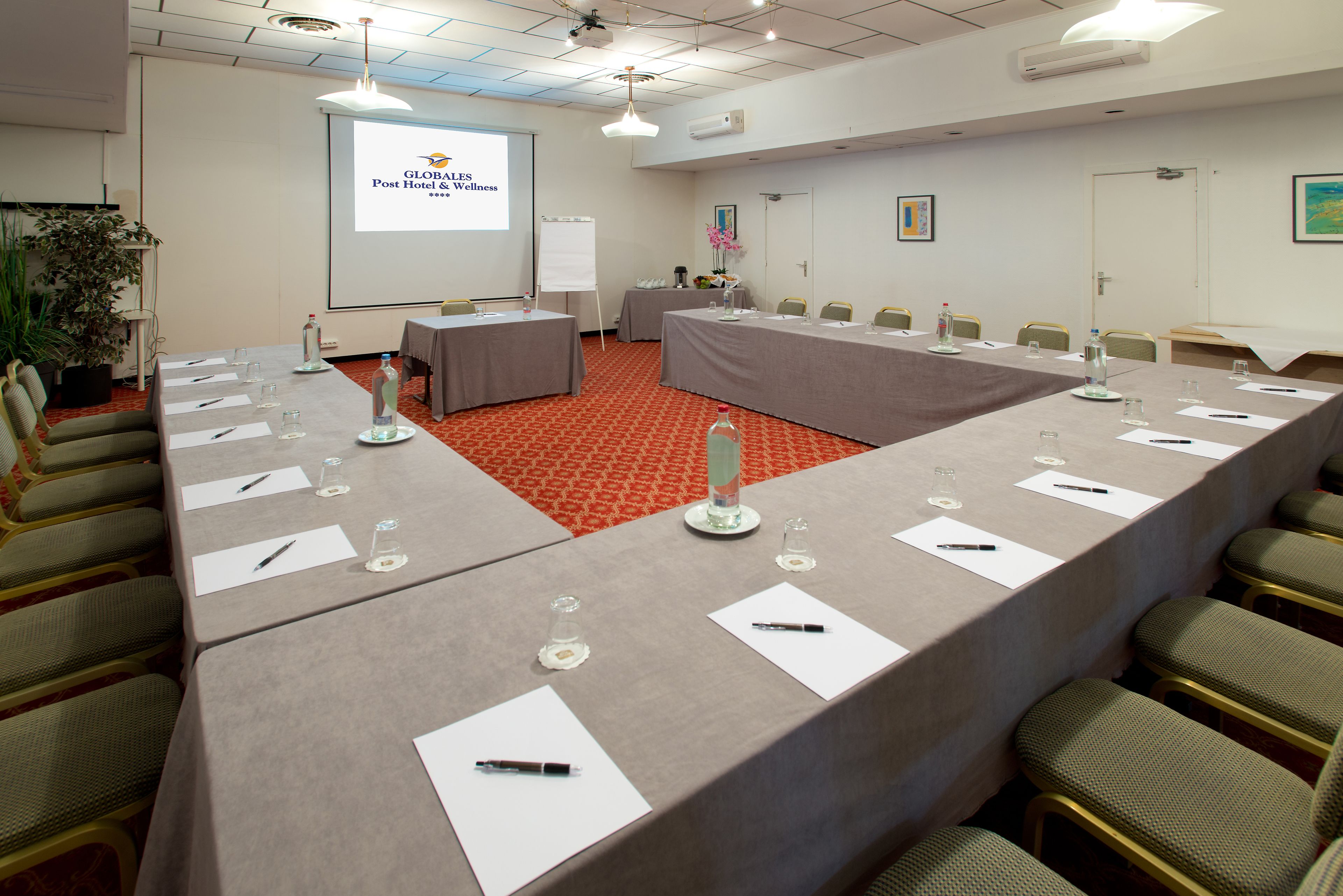 A conference room with a long table, chairs, a projector screen, and a whiteboard.
