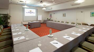 A conference room with a long table, chairs, a projector screen, and a whiteboard.