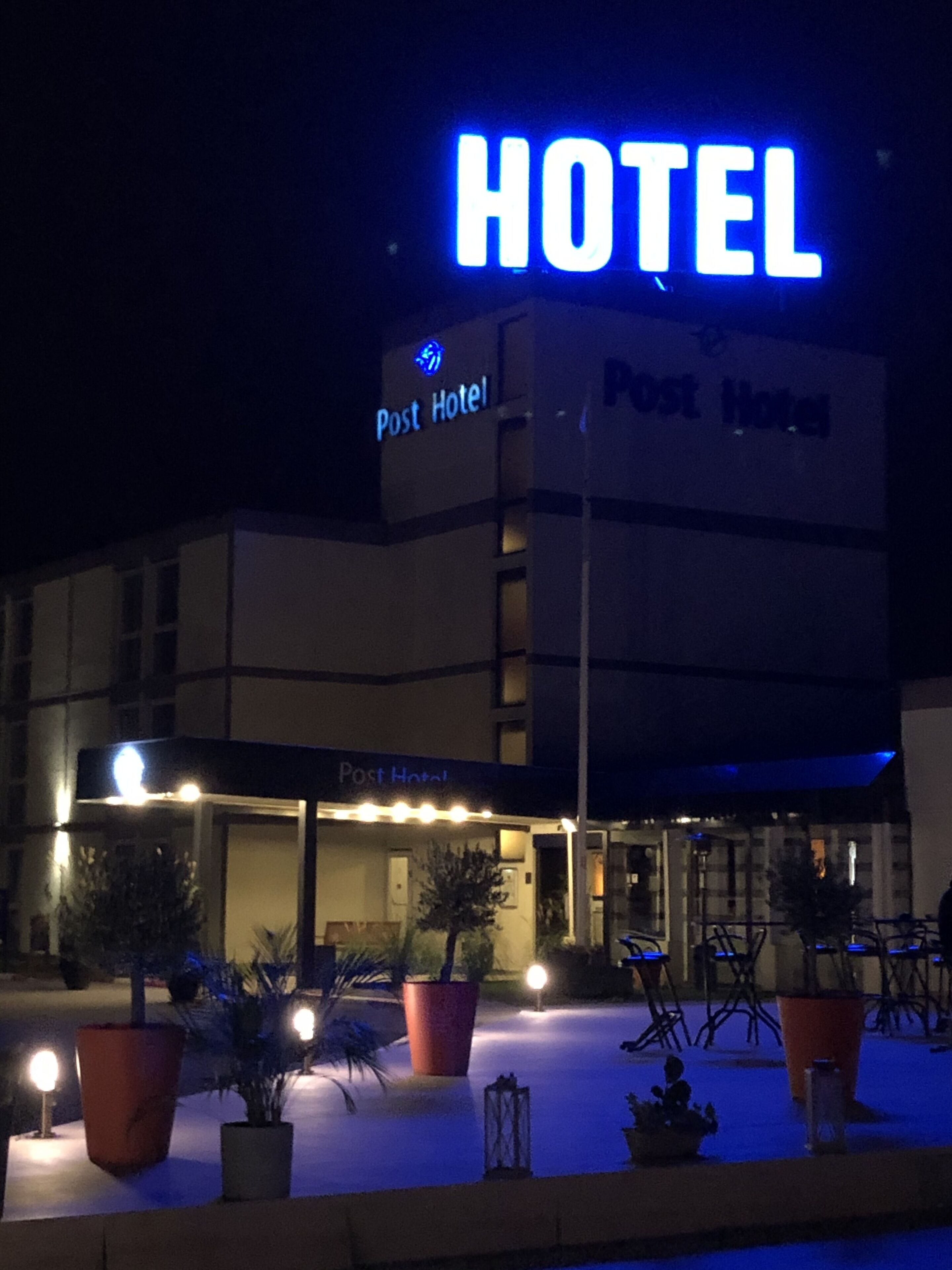 Un hôtel appelé « Post Hotel », reconnaissable à son enseigne lumineuse bien visible.