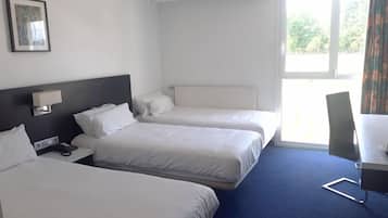 Camera d'albergo con due letti, una scrivania, una sedia e una finestra con tende.