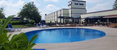 A hotel with a swimming pool, lounge chairs, and outdoor seating areas.