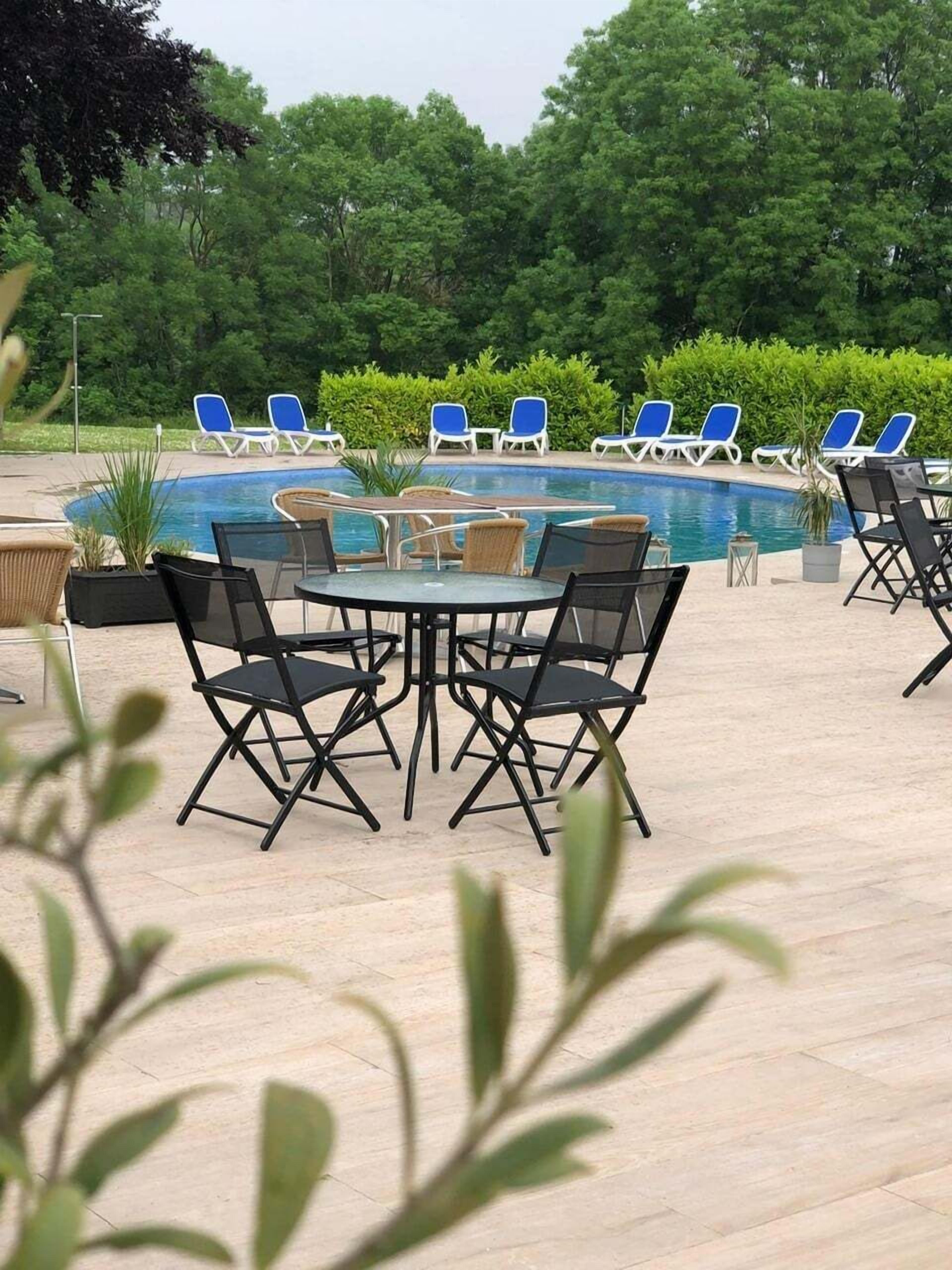 Un área junto a la piscina con sillones, una mesa y sillas.