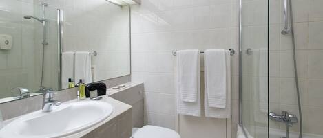 Un baño moderno con ducha de vidrio, lavamanos blanco y retrete.