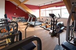 Un gimnasio con cintas de correr, bicicletas estáticas y máquinas de pesas.
