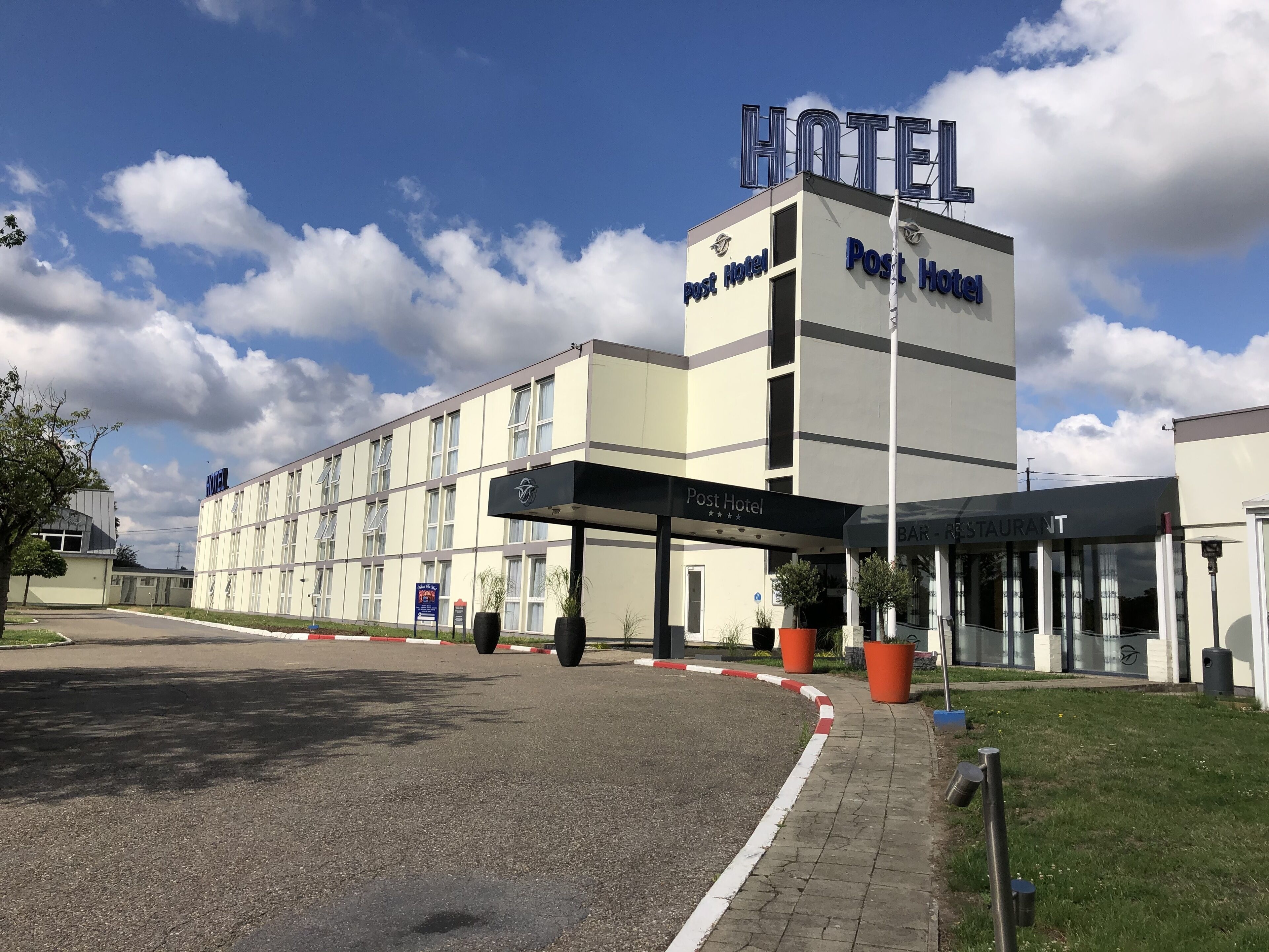 A Post Hotel with a modern facade, a covered entrance, and a visible restaurant area.