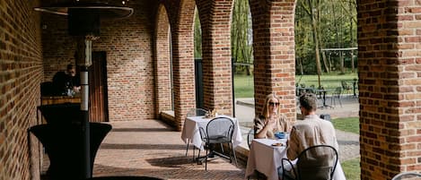 An outdoor dining area with brick arches, tables, and chairs.