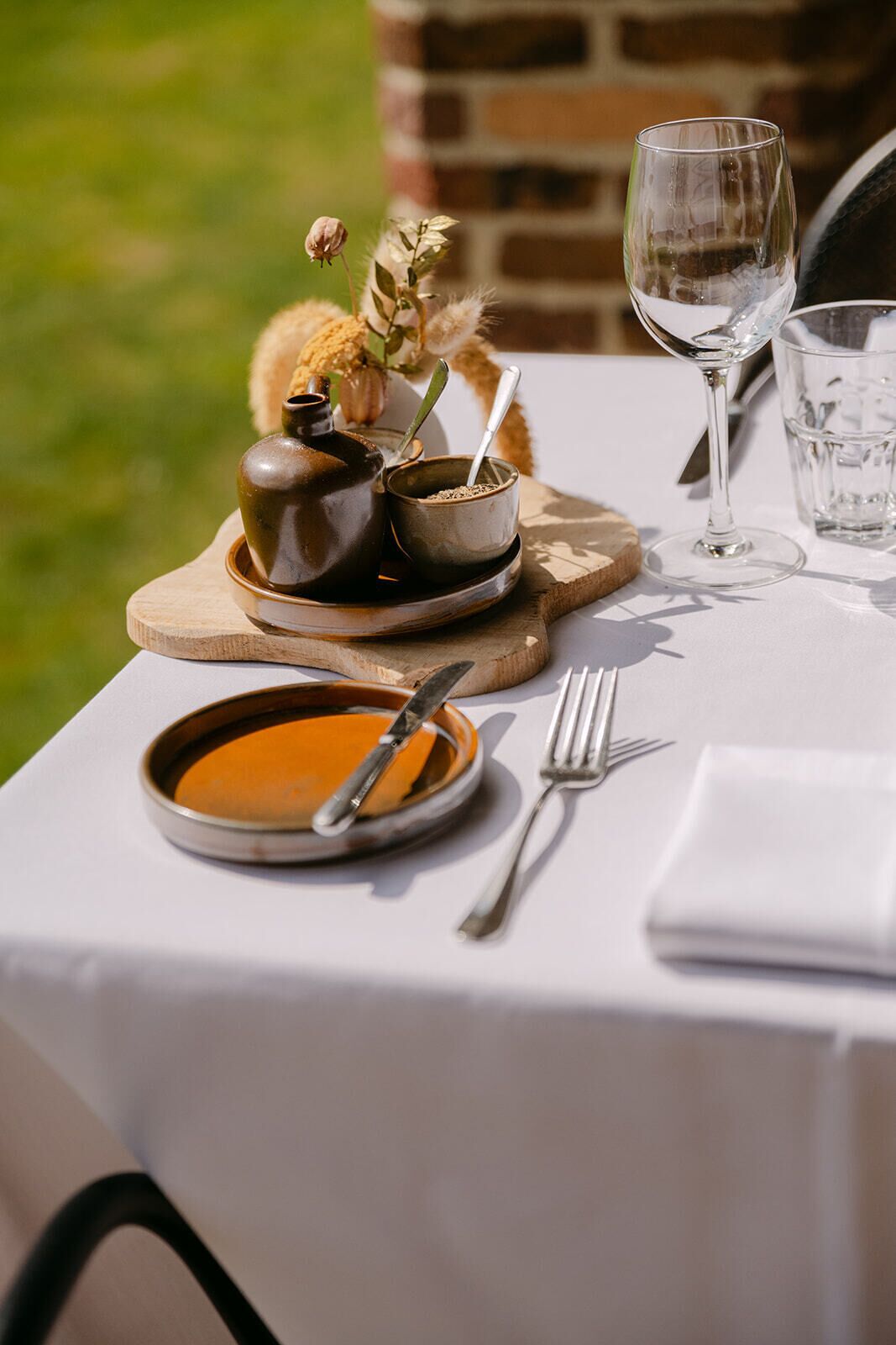 A table set with a bowl of soup, a spoon, a fork, a wine glass, and a small cup with a spoon.