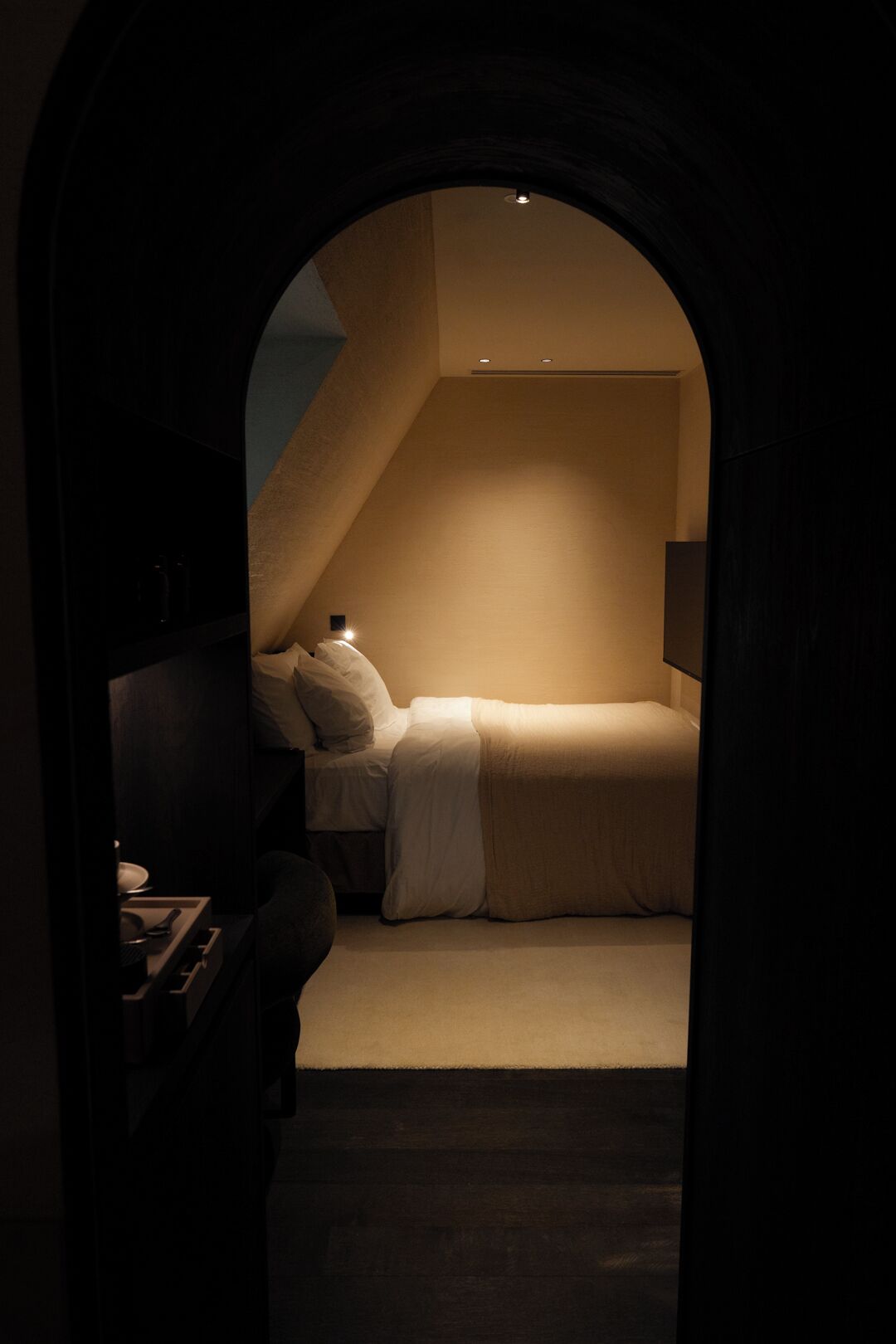 A dimly lit room with a bed, a desk, and a chair.