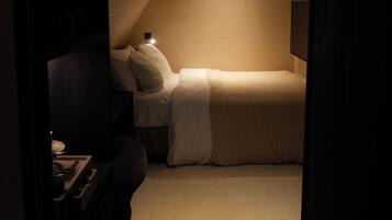 A dimly lit room with a bed, a desk, and a chair.