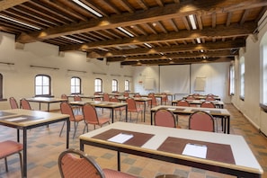 A conference room with wooden beams, tables with chairs, and large windows.