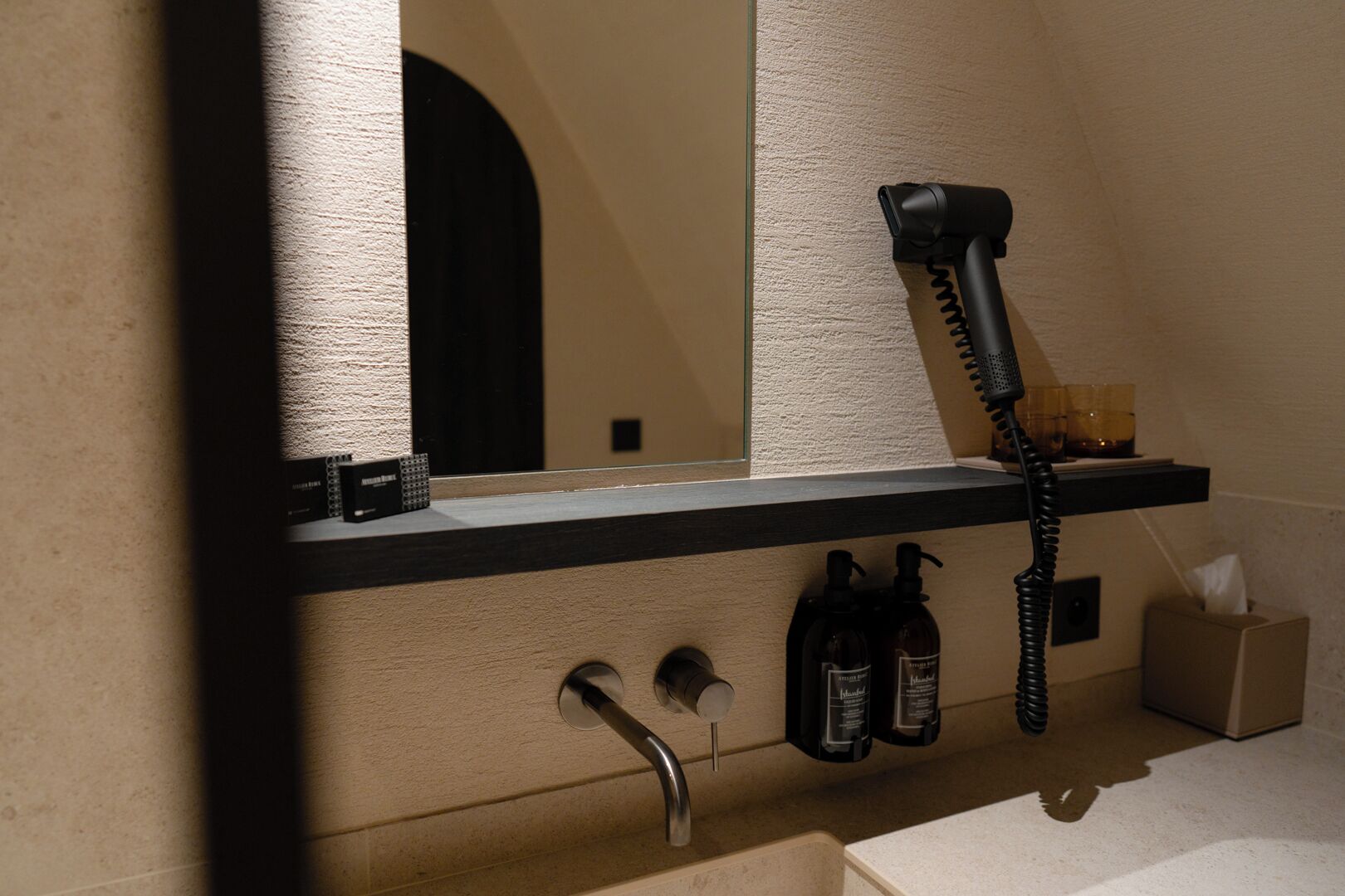 Ein Badezimmer mit Spiegel, Fön und zwei Shampoo-Flaschen.