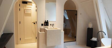 A modern bathroom with a freestanding sink, a mirror, and a shower area.