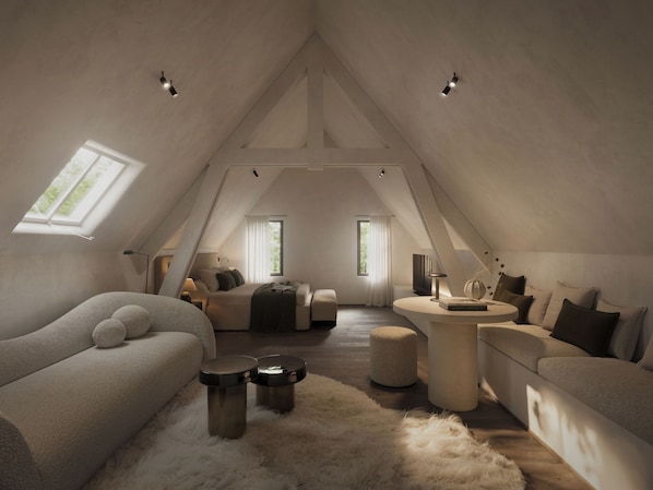 A spacious attic bedroom with a high ceiling, a large window, a cozy sofa, a round coffee table, and a fluffy rug.