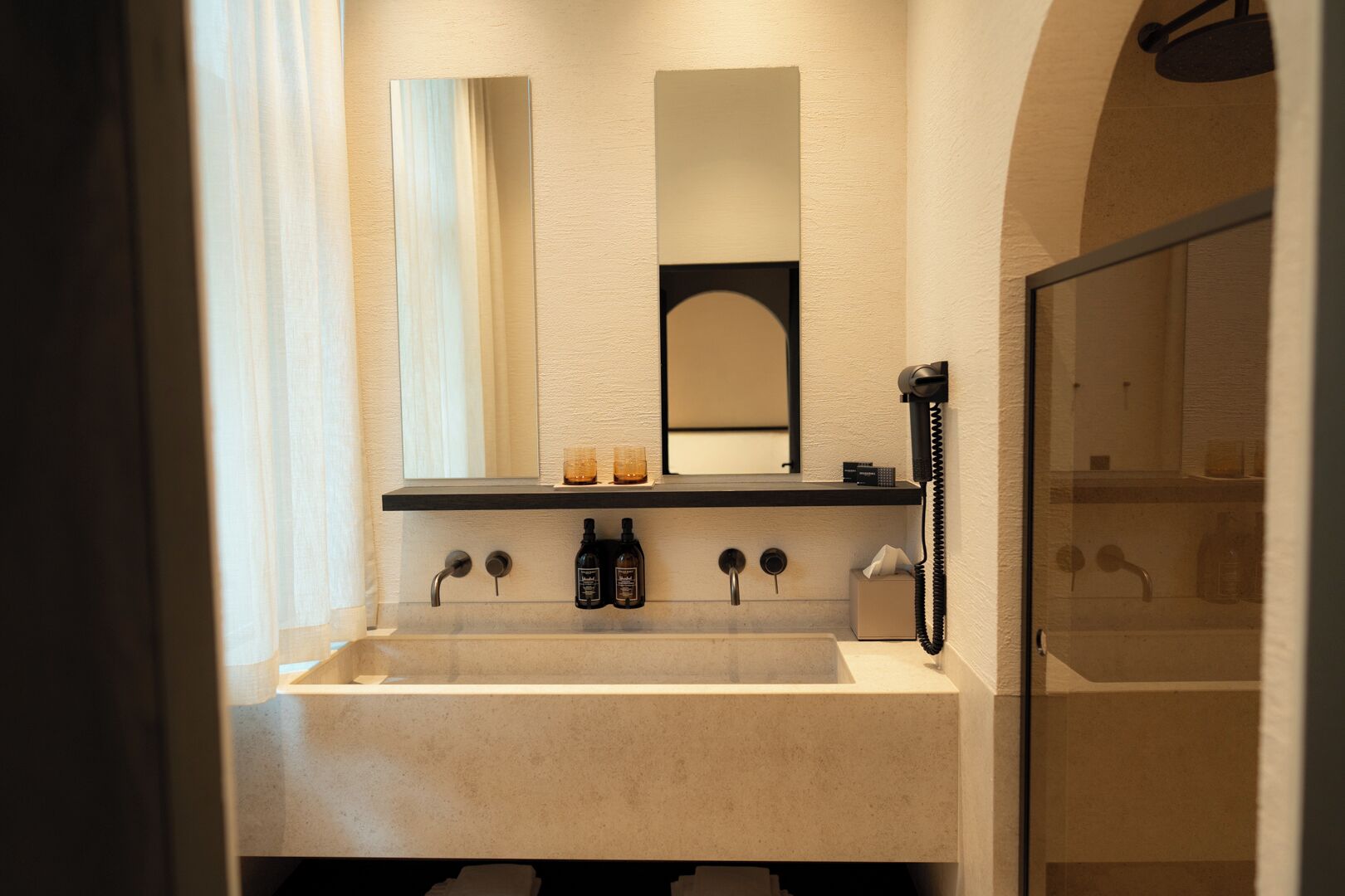 Een badkamer met een groot wastafel, een spiegel, een handdoekhouder en een douche.