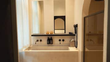 Een badkamer met een groot wastafel, een spiegel, een handdoekhouder en een douche.