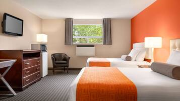 A hotel room with two beds, a desk, a chair, a TV, and a window with curtains.