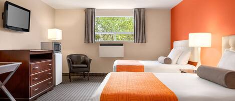 A hotel room with two beds, a desk, a chair, a TV, and a window with curtains.