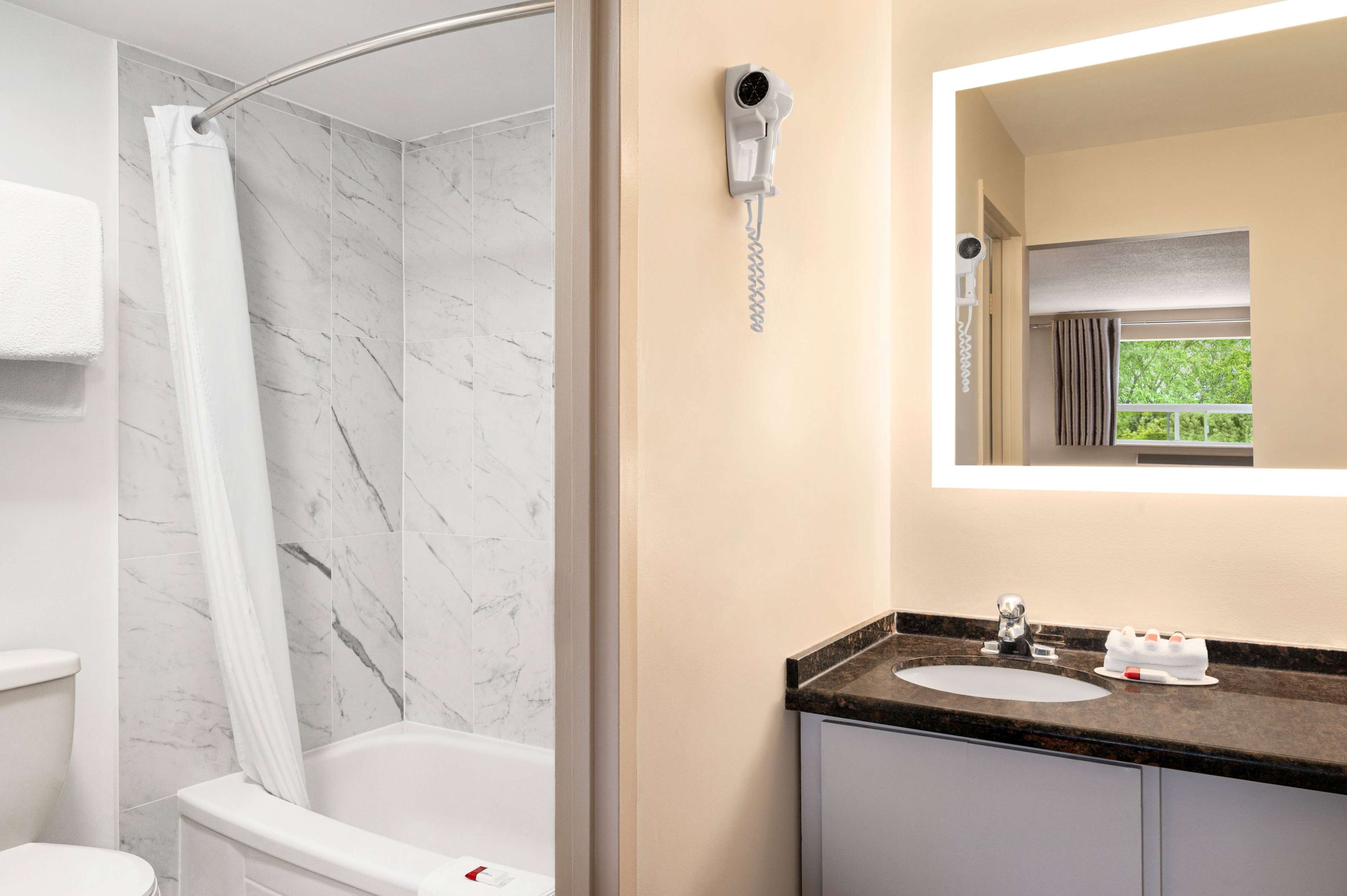 A bathroom with a shower, toilet, and sink with a mirror above.