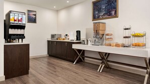 A modern kitchen with a coffee machine, microwave, and a buffet counter with bread and fruit. - Howard Johnson by Wyndham Gravenhurst (Gravenhurst)